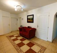 Predaj RD v Šali s bazénom - Chodba v rodinnom dome s červeným kreslom a dlažbou.