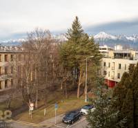 Rezervované: Na predaj pekný 2-izbový byt v centre mesta Poprad - Výhľad na zasnežené Tatry z Murgašovej ulice v Poprade, obklopené zeleňou a budovami.