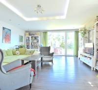 HROZNOVÁ, 4-i RD, 161 m2 – novostavba, krb, klíma, krásna záhrada - Obývacia izba v rodinnom dome s pohovkou, kreslom, knižnicou a presklenými dverami.