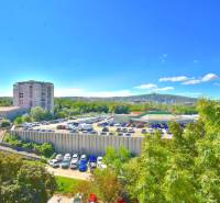 BAKOŠOVA, 1-i byt, 43 m2 – nerušený VÝHĽAD NA KARPATY - Výhľad na parkovisko a okolie v Bratislave - Lamači z Bakošovej, zachytávajúci zeleň a budovy.