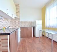 BAKOŠOVA, 1-i byt, 43 m2 – nerušený VÝHĽAD NA KARPATY - Kuchyňa 1-izbového bytu s podlahou s dreveným dekorom, sklenený stôl a spotrebiče.