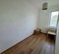 Prenájom 4 izbový byt, Čsl. Parašutistov, Bratislava III. Nové Mesto - Izba v 4-izbovom byte s jednoduchým nábytkom a podlahou s dreveným dekorom.