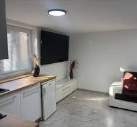 Dom za cenu bytu- komplet prerobený RD 3 izb. Blatné  - Obývacia miestnosť v rodinnom dome s bielou kuchynskou linkou a tmavohnedou pohovkou.