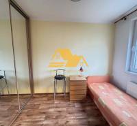 Prenajmem 3 izbový byt na sídlisku Juh v Nových Zámkoch - Izba s posteľou, skrinkou a podlahou s dreveným dekorom v 3-izbovom byte.