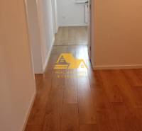 Prerobený 2 izbový byt s balkónom v Nových Zámkoch - Chodba s podlahou s dreveným dekorom v 2-izbovom byte, neutrálne steny.