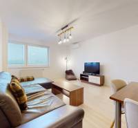 | Svetlý priestranný 2 izbový byt | parkovanie | REZERVOVANÝ - Obývacia izba s pohovkou, televíziou a podlahou s dreveným dekorom v 2-izbovom byte.