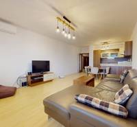 | Svetlý priestranný 2 izbový byt | parkovanie | REZERVOVANÝ - Obývačka 2-izbového bytu s podlahou s dreveným dekorom, veľkou sedačkou a televíziou.