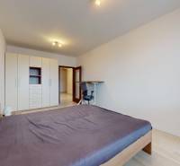 | Svetlý priestranný 2 izbový byt | parkovanie | REZERVOVANÝ - Spálňa v 2-izbovom byte s posteľou, skriňou, stolom a podlahou s dreveným dekorom.