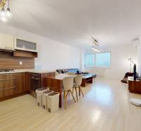 | Svetlý priestranný 2 izbový byt | parkovanie | REZERVOVANÝ - Obývacia izba s kuchynským kútom, podlahou s dreveným dekorom a pohovkou v 2-izbovom byte.