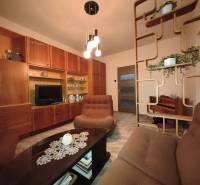 NA PREDAJ • 3i BYT S LOGGIOU • KALINČIAKOVA ULICA, SENICA - Obývačka v 3-izbovom byte s nábytkom z dreva a dekoratívnymi policami.