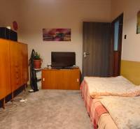 NA PREDAJ • 3i BYT S LOGGIOU • KALINČIAKOVA ULICA, SENICA - Izba v 3-izbovom byte s kobercovou podlahou, posteľou a dreveným nábytkom.