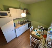 PREDAJ EXKLUZÍVNE: 1i byt s balk.; 41,02 m2; POPRAD; 124.200€ - Kuchyňa so zelenými stenami, bielymi skrinkami a podlahou s dreveným dekorom v 1-izbovom byte.