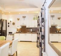 Centrum Košíc - 2-izb.tehlový byt s parkovaním vo dvore - Kuchyňa 2-izbového bytu s podlahou s dreveným dekorom, bielymi skrinkami a stolom.