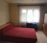 Predám Rodinný dom v Strekove - Spálňa v rodinnom dome s jednoduchým nábytkom a červenou posteľou.