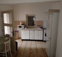 Predám Rodinný dom v Strekove - Kuchyňa v rodinnom dome s bielymi skrinkami, mikrovlnkou a chladničkou.