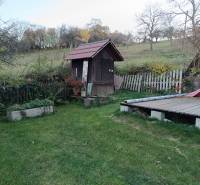 Samota Nová Baňa – Štále s hospodárskymi stavbami  - Záhrada s trávnikom a drevenou šmykľavkou, obklopená prírodou. V pozadí mierne svahy.