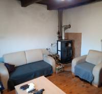 Samota Nová Baňa – Štále s hospodárskymi stavbami  - Rodinný dom s drevenou podlahou, pohovkou, kreslom a krbovými kachľami na drevo.