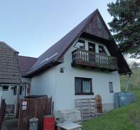 Samota Nová Baňa – Štále s hospodárskymi stavbami  - Rodinný dom so šikmou strechou, balkónom a drevenými prvkami v prírodnom prostredí.