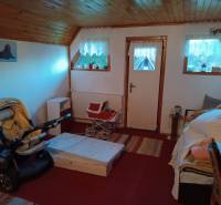 Samota Nová Baňa – Štále s hospodárskymi stavbami  - Izba v rodinnom dome s kočíkom, dreveným stropom a záclonami na oknách.