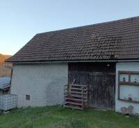 Samota Nová Baňa – Štále s hospodárskymi stavbami  - Na obrázku vidieť rodinný dom s drevenými dverami a sedlovou strechou na svahovitom pozemku.