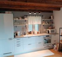 Rekreačná chata Nová Baňa - Drozdovo - Kuchyňa v chate s dreveným stropom, bielymi skrinkami, širokým oknom a otvorenými policami.