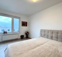 Súčasný 2-izbový byt v novostavbe – Matadorka  - Svetlá spálňa s posteľou, podlahou s dreveným dekorom a pohľadom z okna.