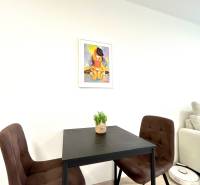 Súčasný 2-izbový byt v novostavbe – Matadorka  - Dvojgarsónka s jedálenským stolom, dvoma stoličkami a obrázkom na stene.