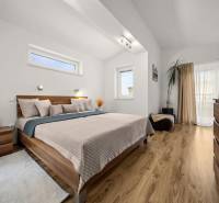 MODERNÝ 5-IZBOVÝ RODINNÝ DOM V ČUNOVE: 180m2 KOMFORTU A TICHA - Spálňa v rodinnom dome s posteľou, dekoratívnymi prvkami a podlahou s dreveným dekorom.