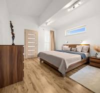 MODERNÝ 5-IZBOVÝ RODINNÝ DOM V ČUNOVE: 180m2 KOMFORTU A TICHA - Spálňa s podlahou s dreveným dekorom, posteľou a komodou v rodinnom dome.