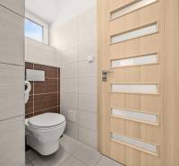MODERNÝ 5-IZBOVÝ RODINNÝ DOM V ČUNOVE: 180m2 KOMFORTU A TICHA - Toaleta v rodinnom dome so svetlými obkladmi a dverami s vertikálnymi pruhmi.