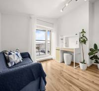 MODERNÝ 5-IZBOVÝ RODINNÝ DOM V ČUNOVE: 180m2 KOMFORTU A TICHA - Izba v rodinnom dome s podlahou s dreveným dekorom, modrou pohovkou a pracovným stolom.