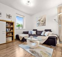 MODERNÝ 5-IZBOVÝ RODINNÝ DOM V ČUNOVE: 180m2 KOMFORTU A TICHA - Obývacia izba v rodinnom dome s pohovkou, skriňou, podlahou s dreveným dekorom a dekoráciami.