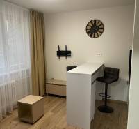 REZERVOVANÉ! Nadštandardný 1-izbový byt, ul. 1. mája, Vráble - Interiér 1-izbového bytu so stolom, stoličkami a podlahou s dreveným dekorom.