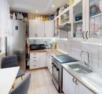 (56 m²) PRÍJEMNÝ 2i BYT NA SÍDLISKU TARČA - Kuchyňa v 2-izbovom byte s bielymi skrinkami a striebornými spotrebičmi.