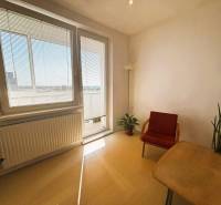 Slnečný dvojizbový byt – 43,5 m² v Bratislave – Vajnory - Svetlá obývacia izba s podlahou s dreveným dekorom v 2-izbovom byte, s červeným kreslom.