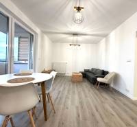 Na prenájom 3 izb. byt, Trenčín, ul.Vl.Predmerského, park.miesto,garáž - Obývačka v 3-izbovom byte s pohovkou, stolom a podlahou s dreveným dekorom.