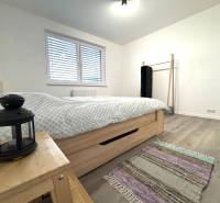 Na prenájom 3 izb. byt, Trenčín, ul.Vl.Predmerského, park.miesto,garáž - Spálňa v 3-izbovom byte s podlahou s dreveným dekorom, posteľou a nočným stolíkom.