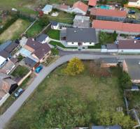 Stavebný pozemok 882 m² | Gajary - Letecký pohľad na obytné pozemky v Gajaroch s priľahlou cestou a domami.