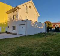 Svetlý 2i byt + 200 m² záhrada | Biely Kostol - Žltý dom s garážou a autom na pozemku v Bielom Kostole.