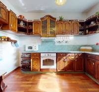 Bývanie ako v raji pri lagúne | Šamorín - Kuchyňa vo Vile s tmavými drevenými skrinkami a podlahou s dreveným dekorom.