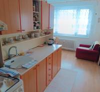 Na predaj veľkometrážny 3 izbový byt Žarnovica - Kuchyňa v 3-izbovom byte s podlahou s dreveným dekorom, vybavená skriňami a pohovkou.