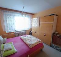 Na predaj veľkometrážny 3 izbový byt Žarnovica - Spálňa v 3-izbovom byte s posteľou a skriňou, okno s oblúkovou záclonou.