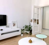 Na prenájom 2 izbový byt, 56 m2, Bratislava, Staré Mesto, Björnsonova - Obývacia izba v 2-izbovom byte s TV, stolíkom a podlahou s dreveným dekorom.