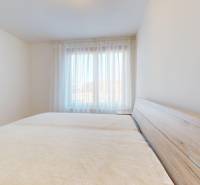| Prémiové bývanie v ZWIRNe I Pekný zariadený 2i byt I - Spálňa v 2-izbovom byte s posteľou pri okne s priesvitnými závesmi.