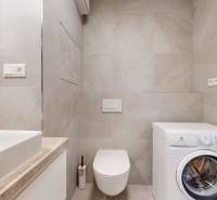 | Prémiové bývanie v ZWIRNe I Pekný zariadený 2i byt I - Kúpeľňa s práčkou, umývadlom a toaletou v 2-izbovom byte. Béžové obklady na stenách.