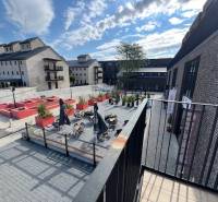 PREDAJ VEĽKORYSÝ 2 IZBOVÝ BYT NOVOSTAVBA DESINGN CENTER - Exteriér Námestia pri Sýpke v Bratislava - Jarovce s terasou a tehlovými budovami.