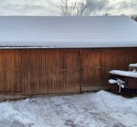 Predaj: Rodinný dom po rekonštrukcii s nadstavbou v Ochodnici (RCZ) - Na fotografii z Ochodnice je drevený skladný prístrešok pri rodinnom dome so snehovou pokrývkou.