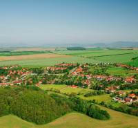 Nemčinany – Podiely na poľnohospodárskej pôde - Letecký pohľad na Nemčiňany, obklopené poľnohospodárskymi a lesnými pozemkami v zelenej krajine.
