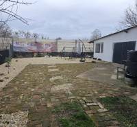 RODINNÝ DOM, HERNÁDKAK, MAĎARSKO - Dvor rodinného domu v Hernádkaku s dlažbou a vonkajším posedením na pozemku.