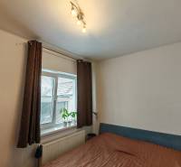 Na predaj rodinný dom v Trnovci nad Váhom - Spálňa v rodinnom dome, s posteľou, poličkami a oknom s dekoračnou rastlinou.